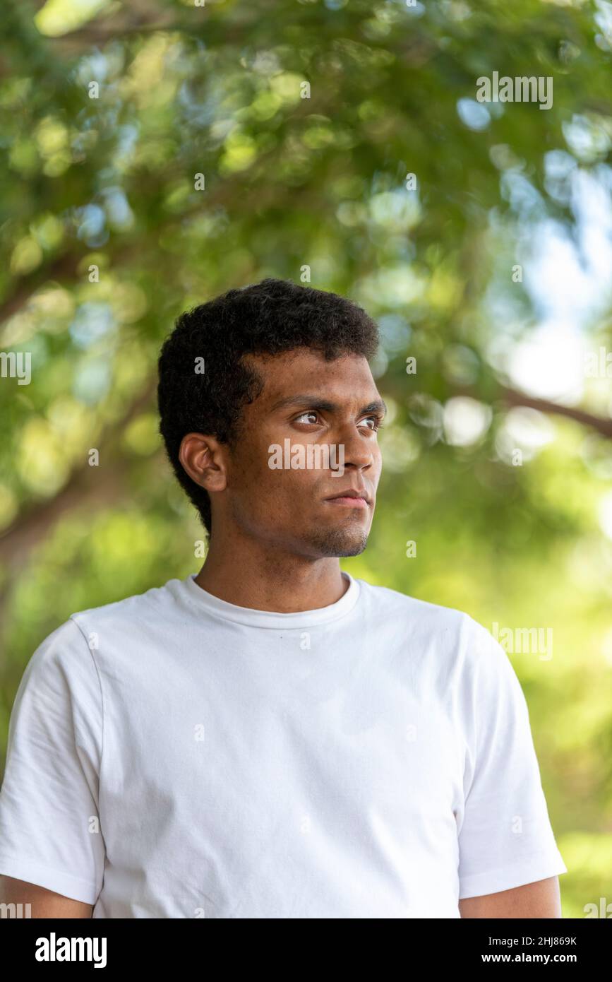 Ritratto di giovane latino sicuro indossando una t-shirt in un parco pubblico. Foto Stock