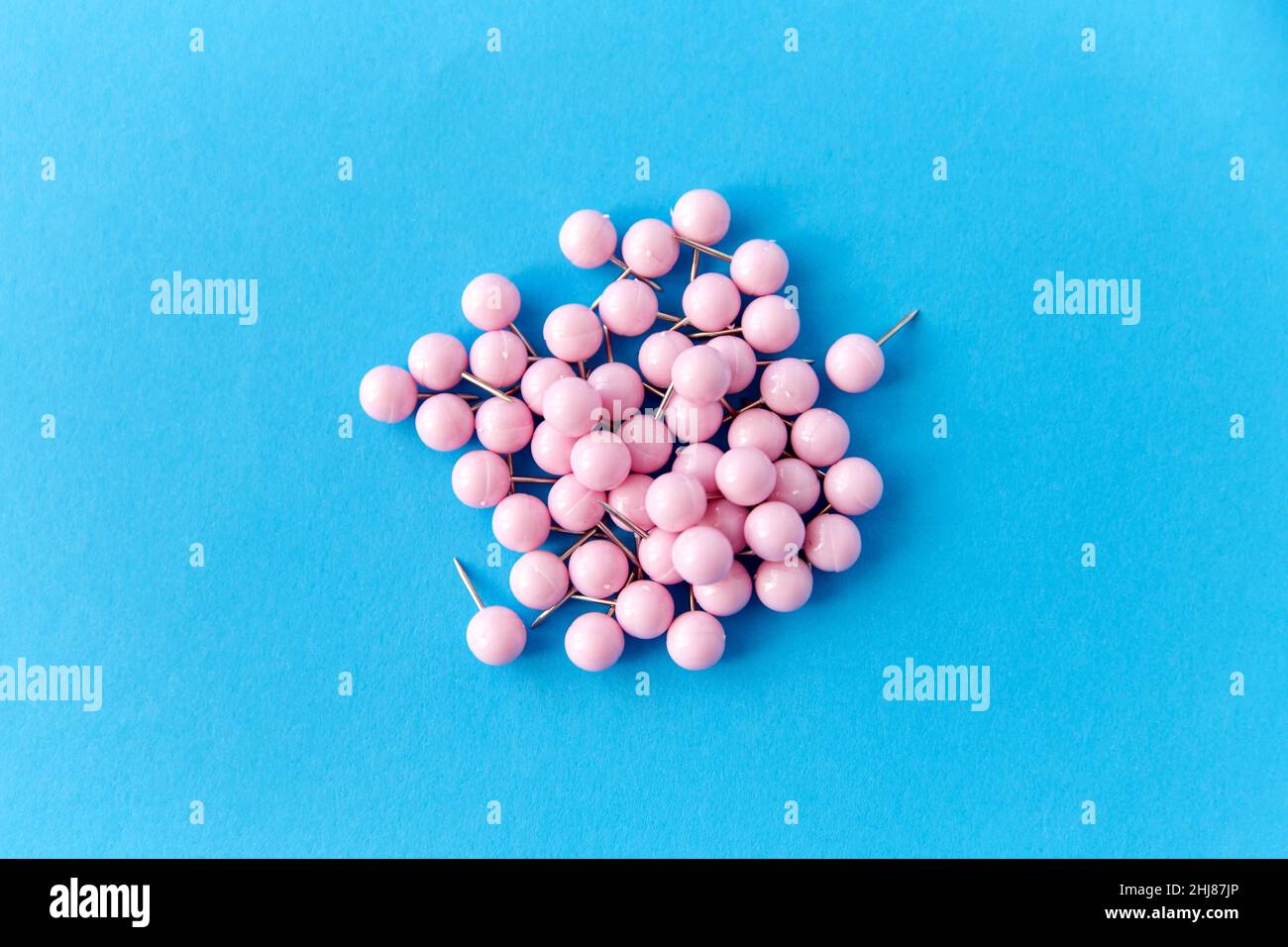 un mucchio di spille rosa da ufficio su sfondo blu Foto Stock