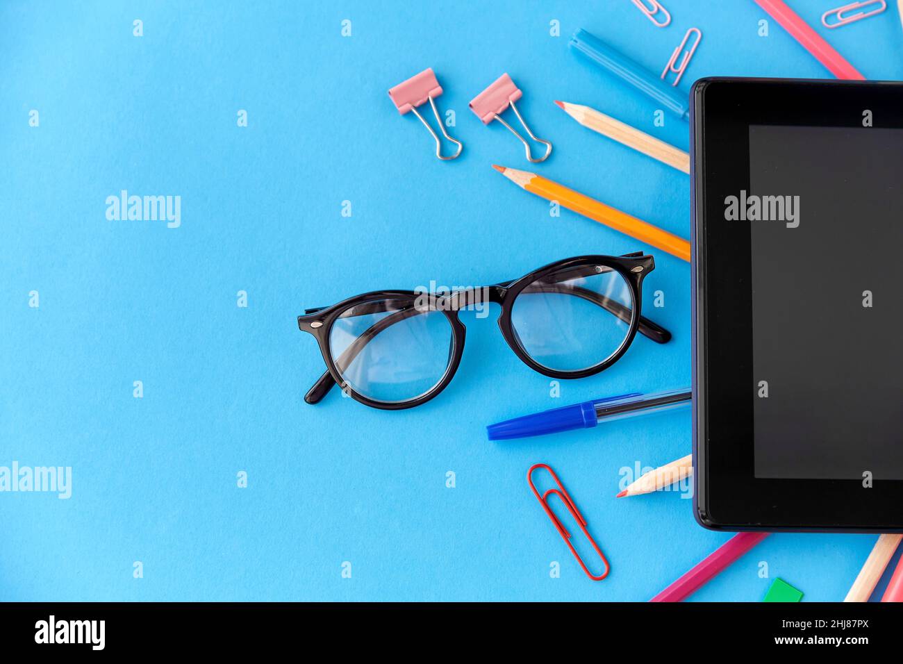 tablet pc e forniture scolastiche su sfondo blu Foto Stock