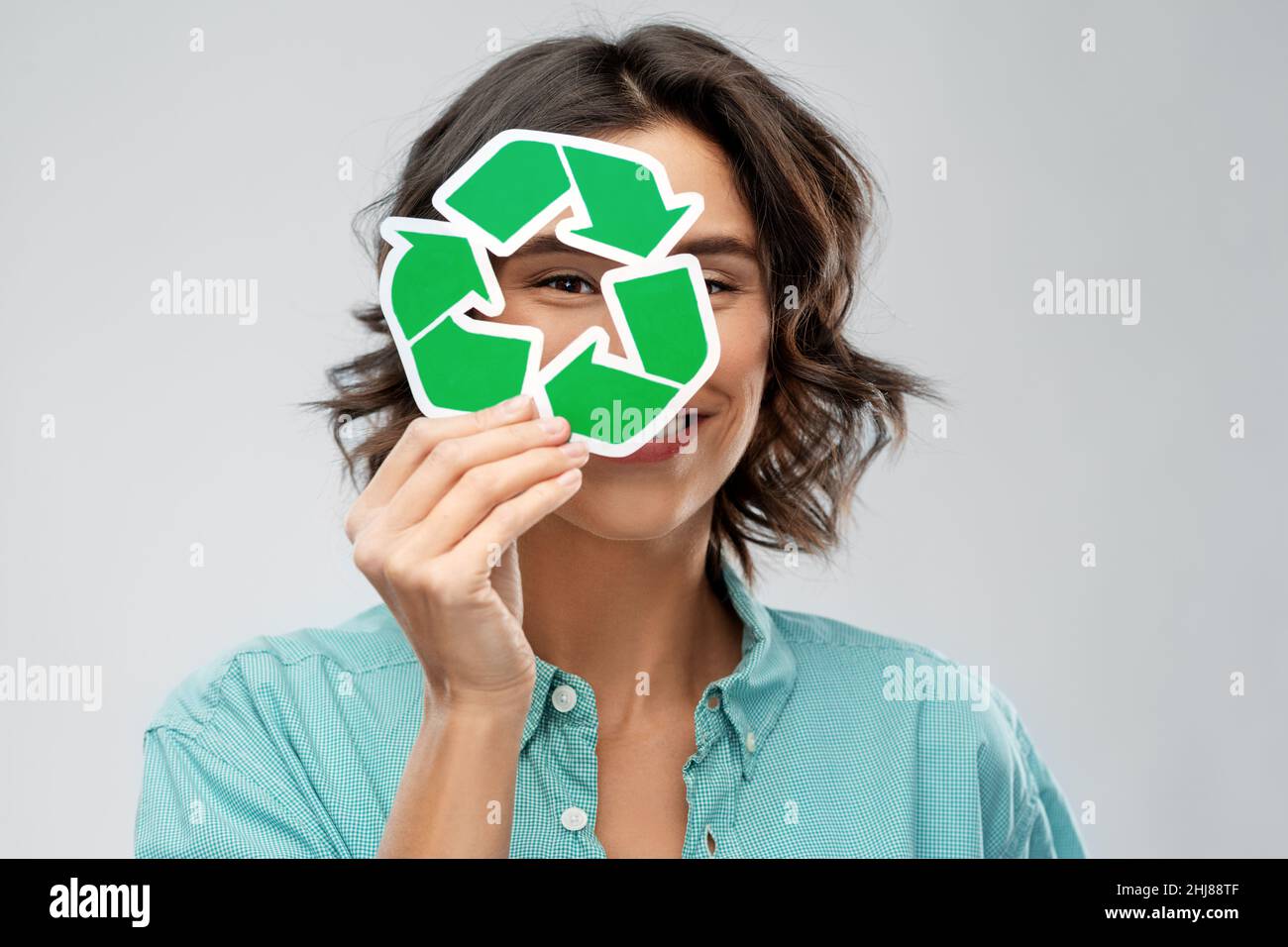 donna sorridente che guarda attraverso il segno verde di riciclaggio Foto Stock