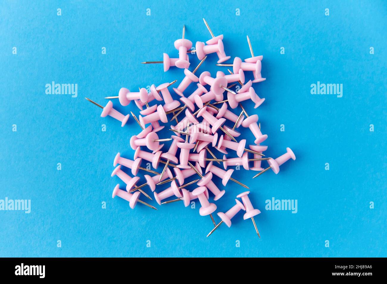 un mucchio di spille rosa da ufficio su sfondo blu Foto Stock