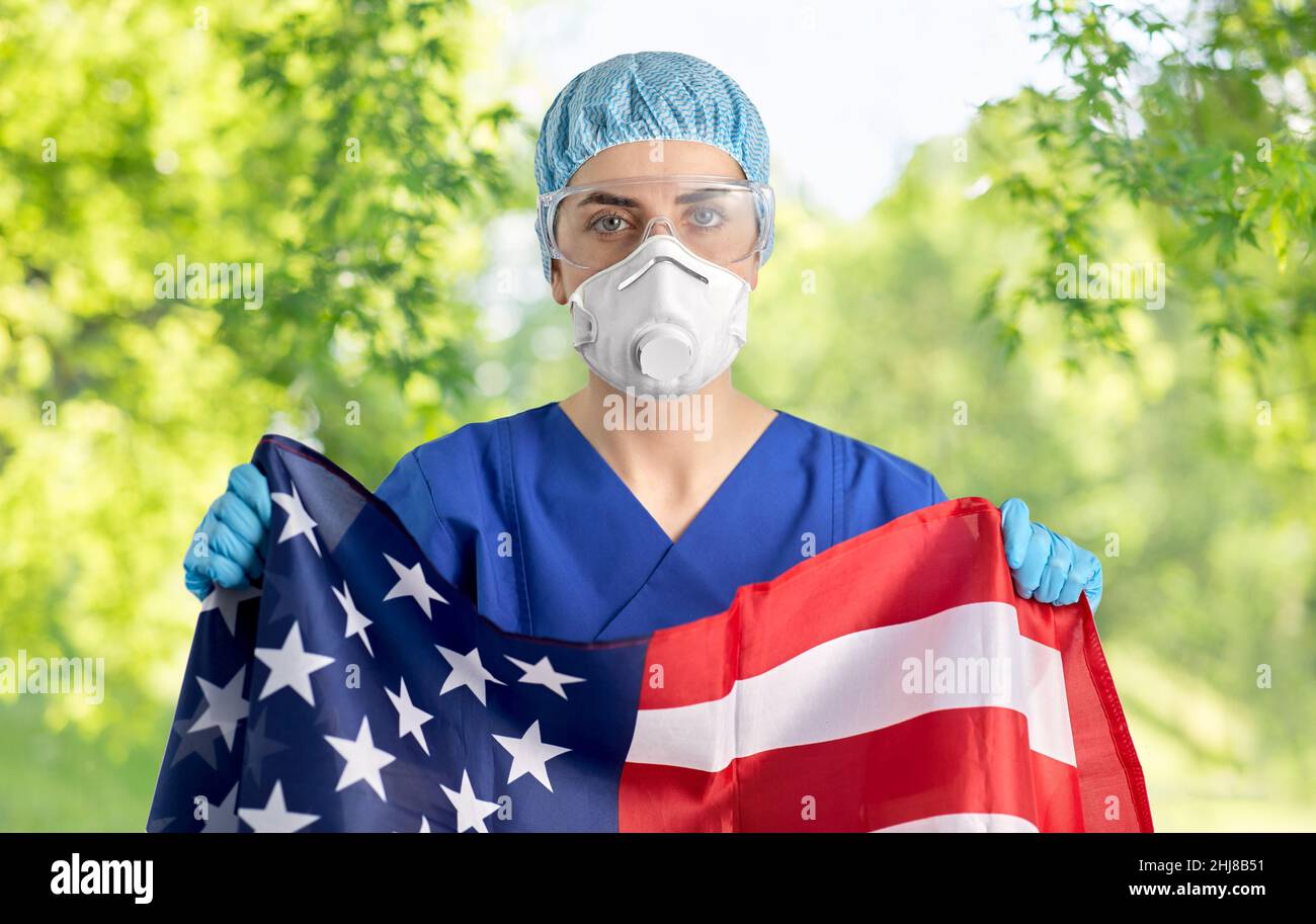 medico in occhiali e maschera che regge bandiera d'america Foto Stock