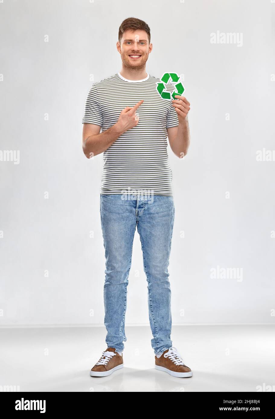 sorridente giovane uomo con cartello verde di riciclaggio Foto Stock