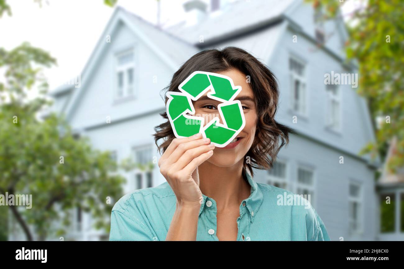 donna sorridente che guarda attraverso il segno verde di riciclaggio Foto Stock