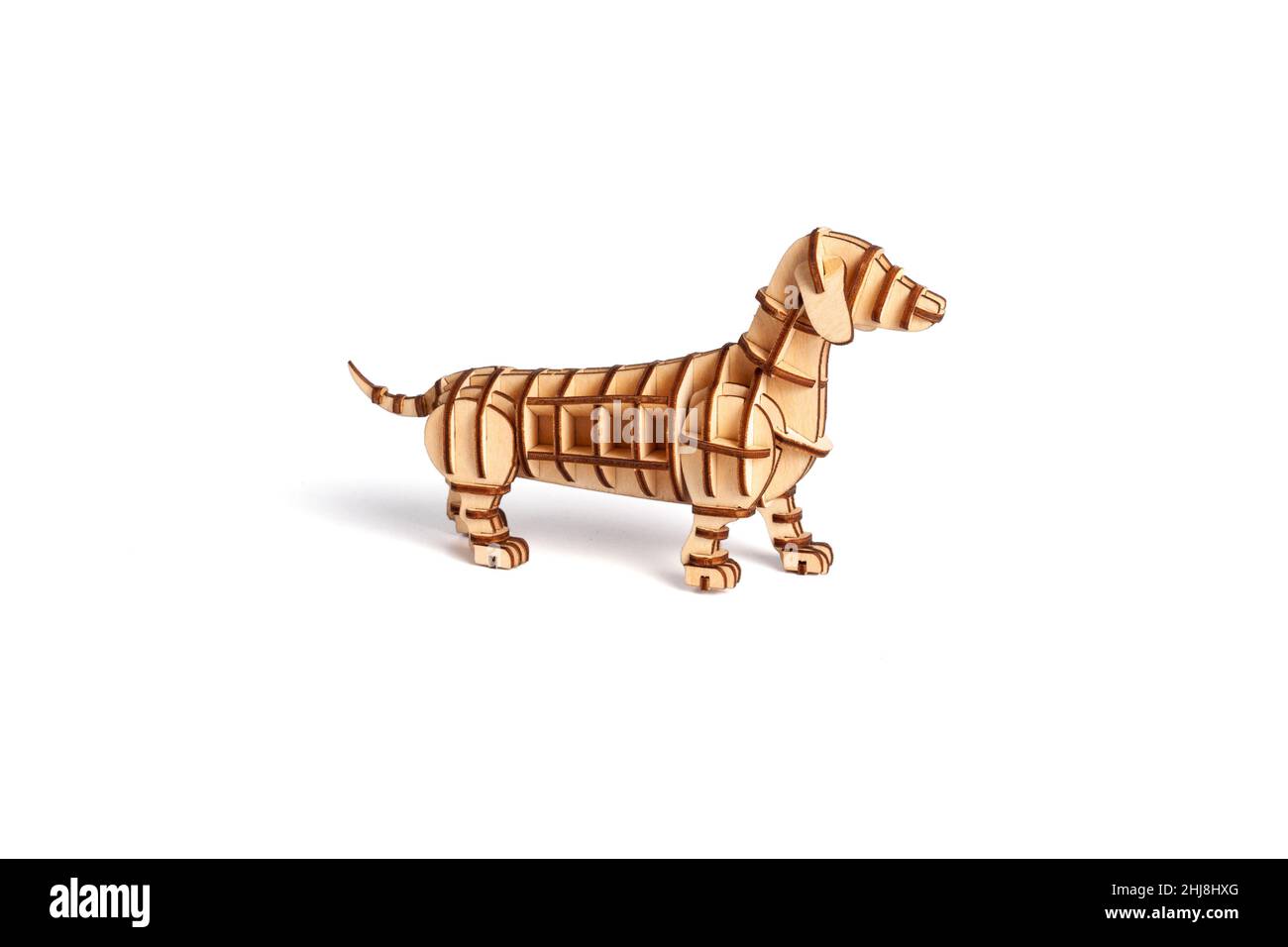 Figurina del cane assemblata da un puzzle di legno maked dalla lavorazione laser. Statuetta TOY dachshund isolata su sfondo bianco Foto Stock