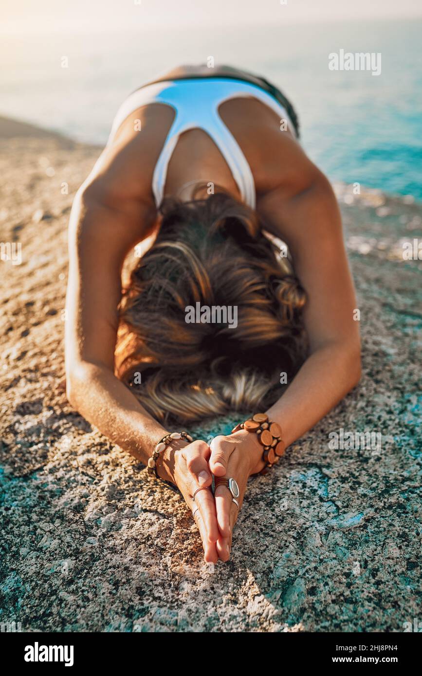 Rimanere sempre umili e gentili. Scatto di una giovane donna che pratica yoga sulla spiaggia. Foto Stock