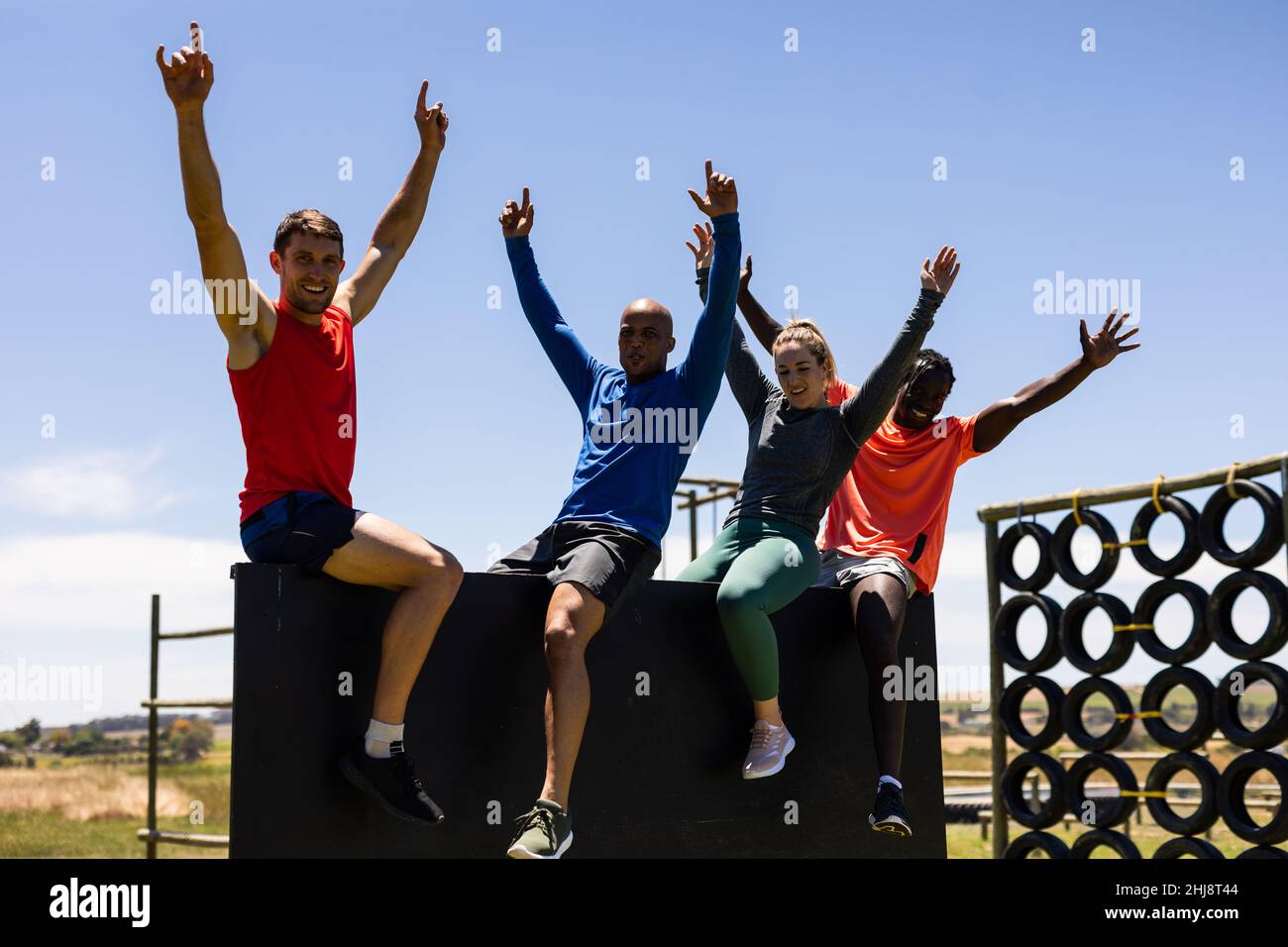 Gruppo di uomini e donne in forma festeggiamenti dopo aver salito un muro di legno al campo di stivali Foto Stock