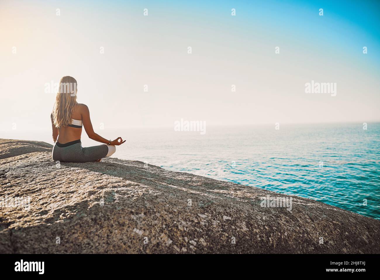 Siate gentili con voi stessi. Foto retrostensiva di una giovane donna che pratica yoga sulla spiaggia. Foto Stock