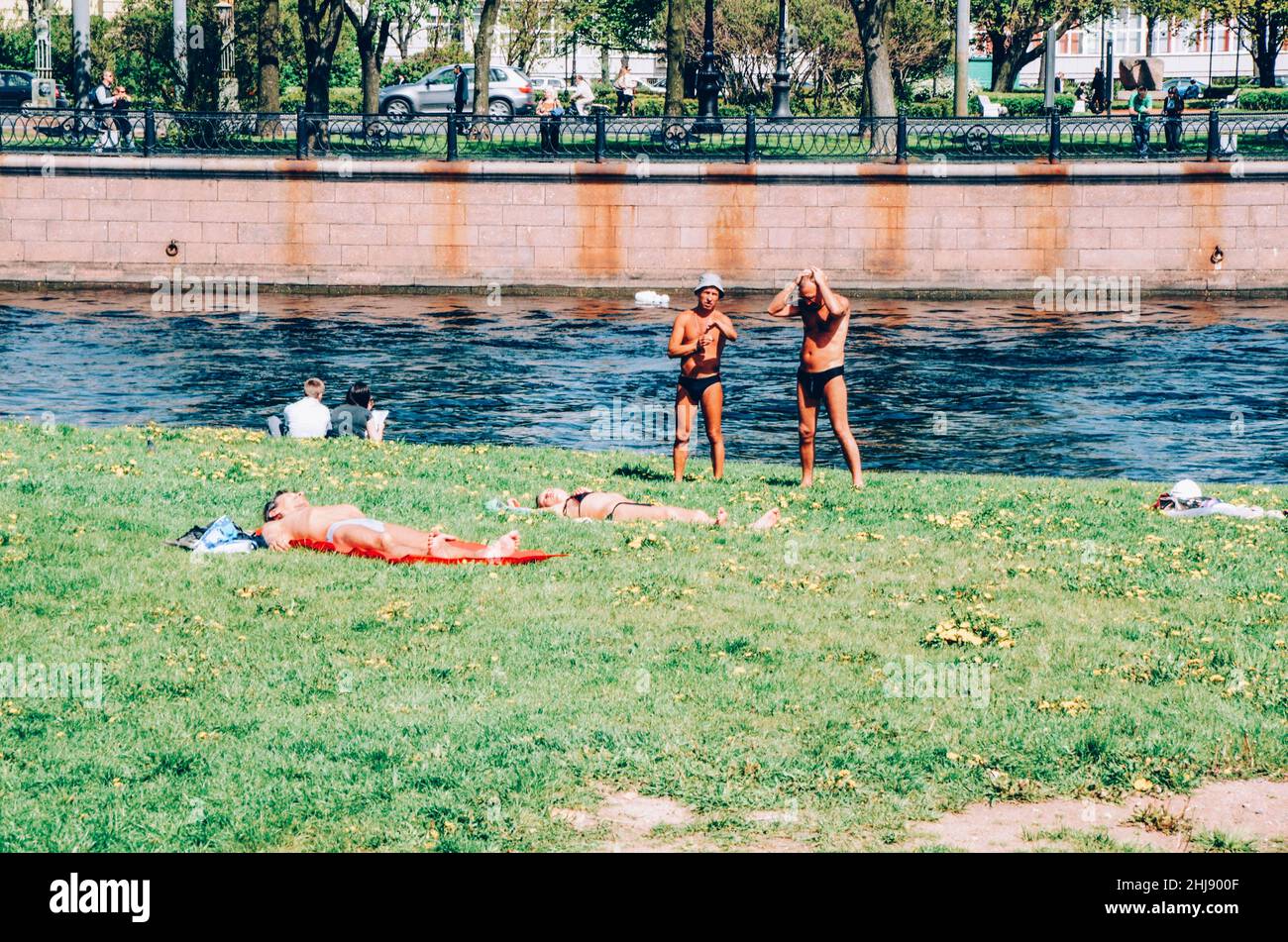 I bagnanti catturano un po' di sole sul fiume Neva a San Pietroburgo, Russia. Foto Stock