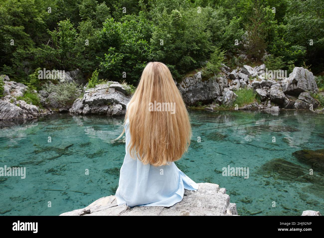 Donna bionda su un lago di montagna in Valbone Foto Stock