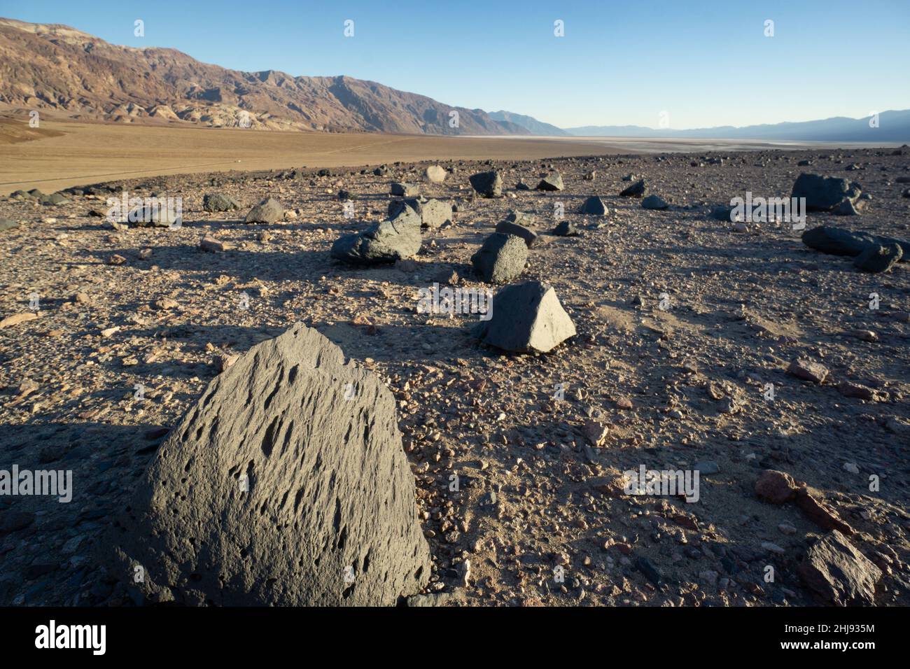 Ventifacts, scolpito da sabbia e polvere soffiata dal vento, Death Valley National Park, California, USA. Montagne nere delimitate da difetti sullo sfondo. Foto Stock