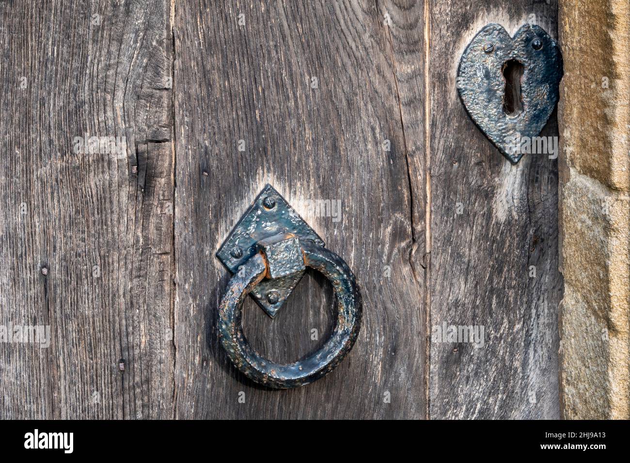 Maniglia per porta in metallo per impieghi pesanti su una vecchia porta in legno Foto Stock