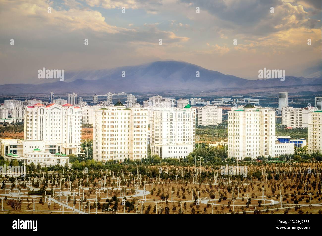 Paesaggio urbano, skyline con edifici alti rivestiti di marmo e nuovi parchi ad Ashgabat, la capitale del Turkmenistan, in Asia centrale. Luce del tramonto dorata. Foto Stock