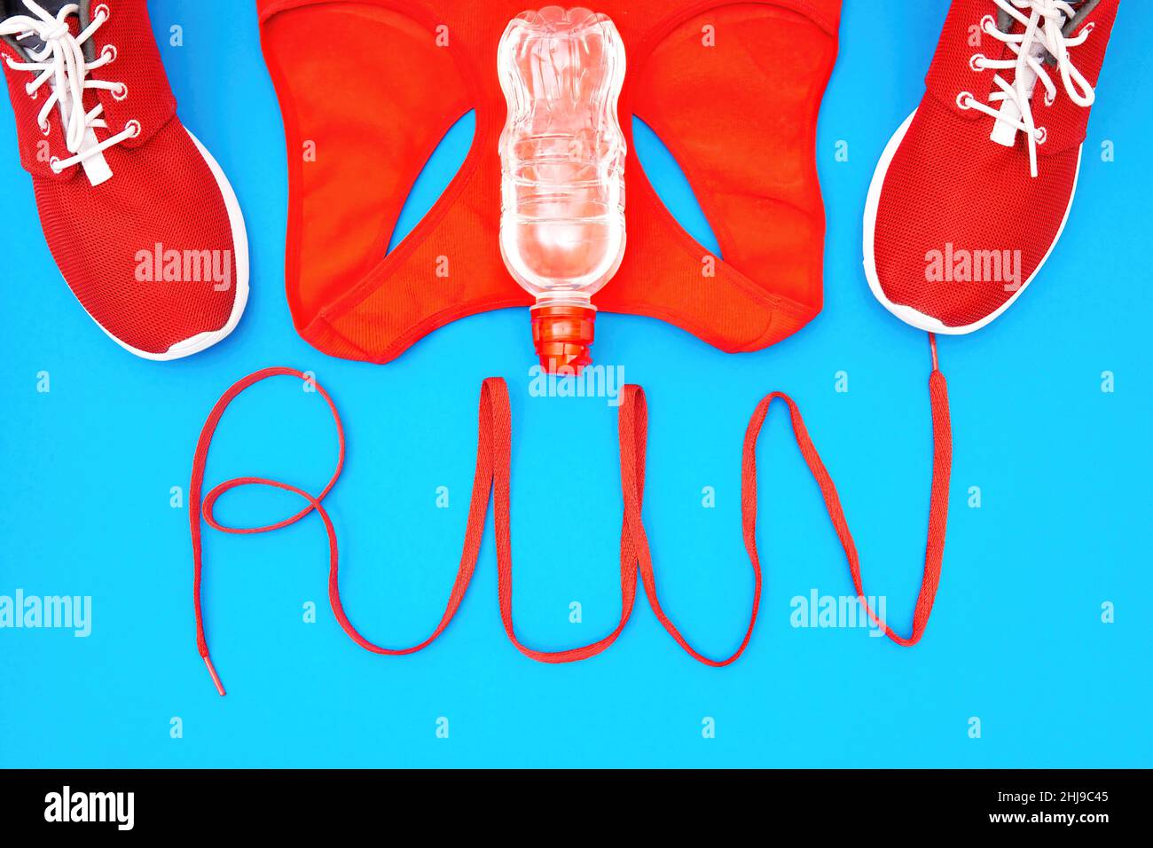Scarpe da running e un carro armato con la scritta RUN fatto da una scarpa su sfondo blu. Concetto di stile di vita attivo creativo. Foto Stock