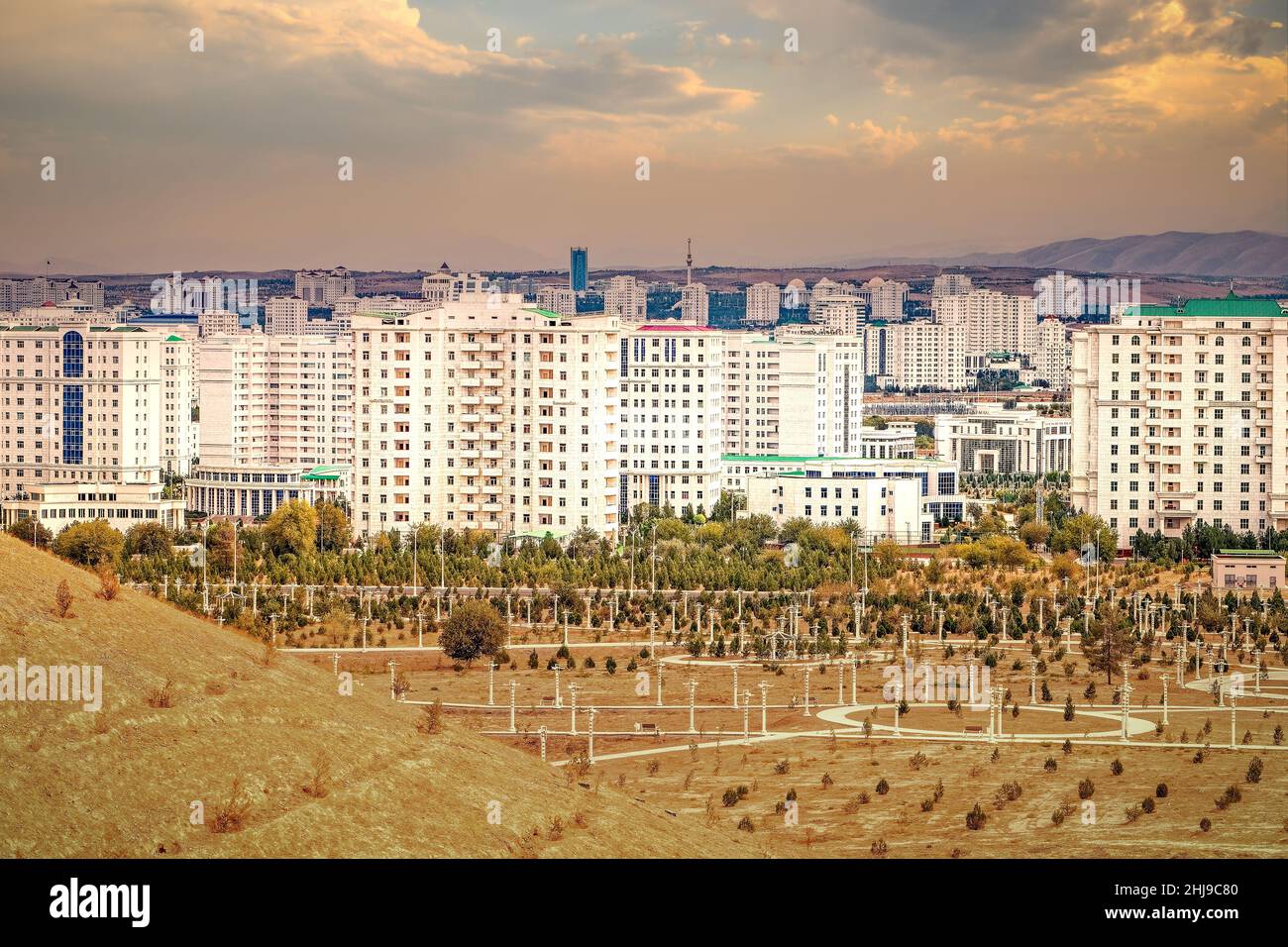 Paesaggio urbano, skyline con edifici alti rivestiti di marmo e nuovi parchi ad Ashgabat, la capitale del Turkmenistan, in Asia centrale. Luce del tramonto dorata. Foto Stock