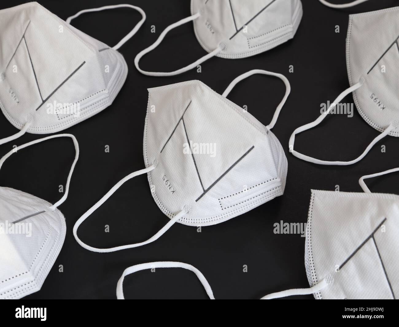 Sul display vengono visualizzate molte maschere per respiratori bianche KN95 pulite e inutilizzate, impostate su uno sfondo nero pieno. Foto Stock
