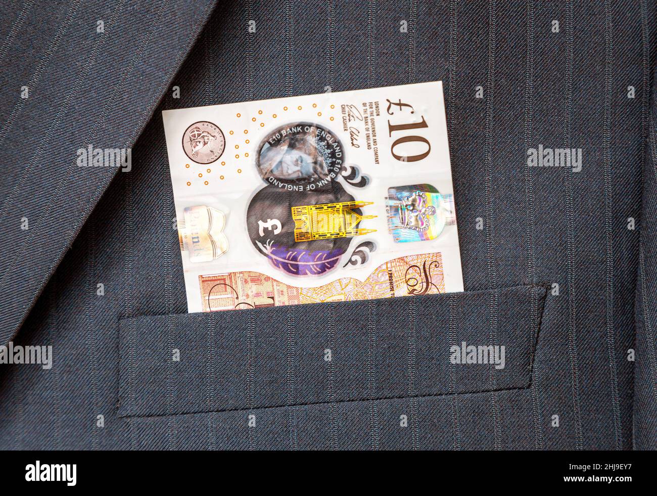 Banconote di sterline britanniche che sporgono dalla tasca del vestito dell'uomo d'affari. Soldi in tasca del vestito di affari Foto Stock