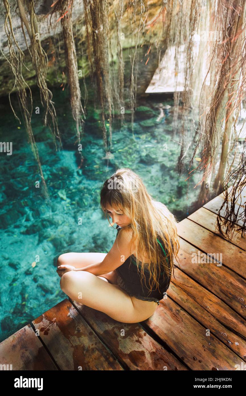 Ragazza seduta in un cenote blu, con giubbotto salvagente Foto Stock