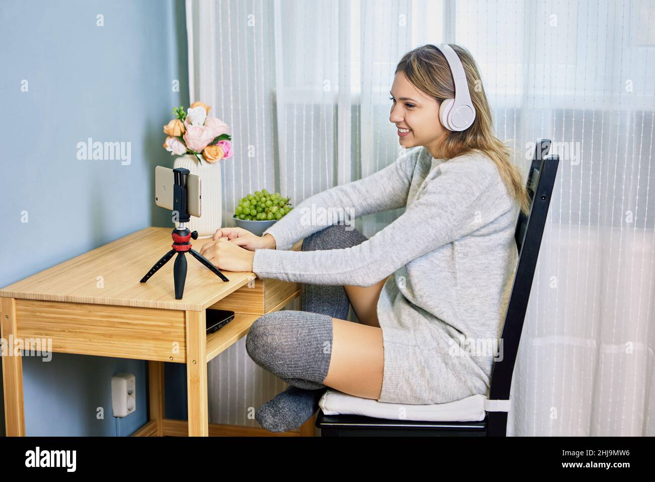 Streaming dal vivo da donna in cuffie che utilizzano il pratico treppiede. Foto Stock