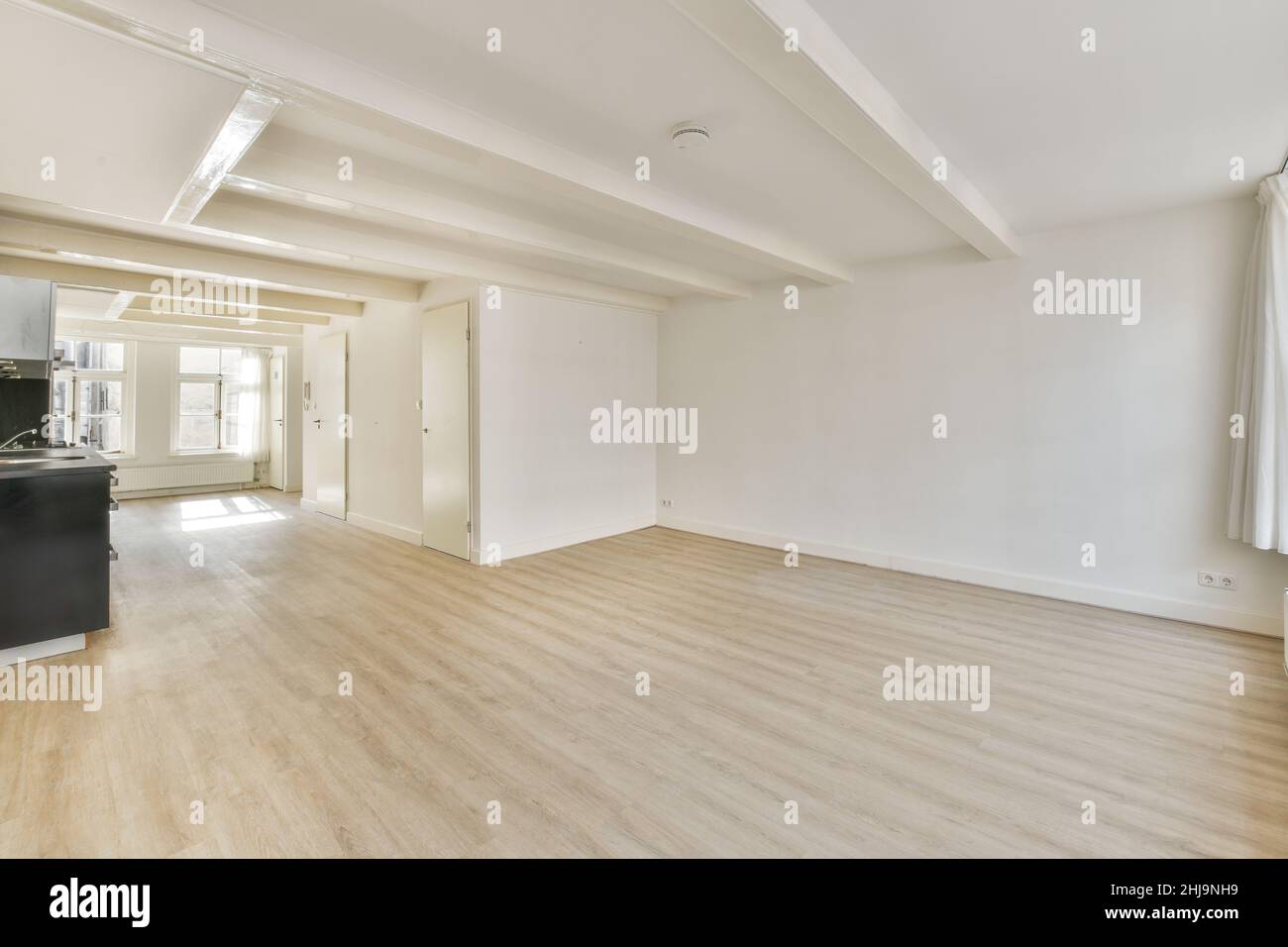 Interno di una luminosa stanza vuota con moderni elettrodomestici da cucina con armadi neri Foto Stock