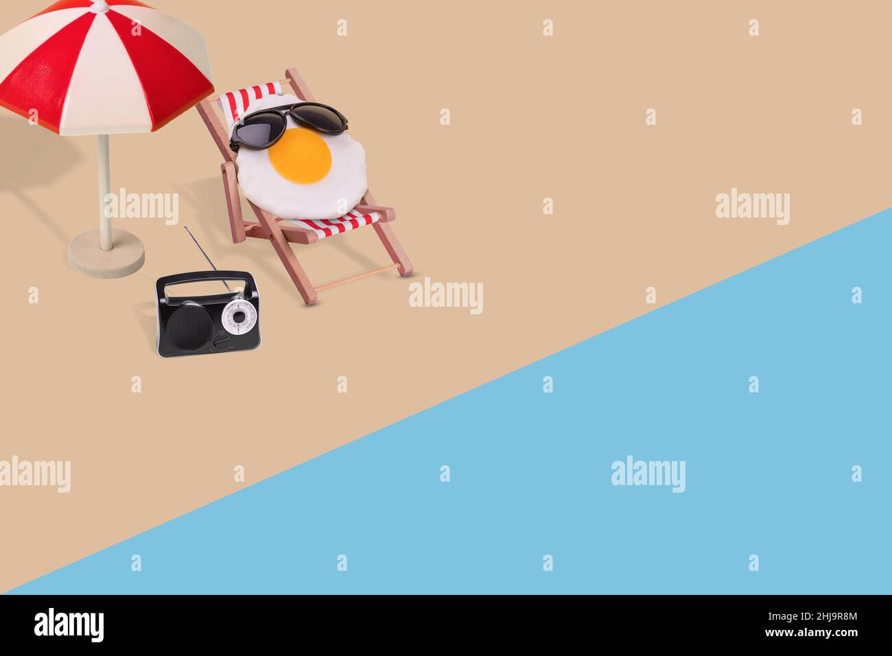 Composizione divertente e creativa composta da ombrellone, radio, uovo fritto con occhiali da sole seduti sulla sedia a sdraio sulla spiaggia. Stagione minima o vacanza estiva Foto Stock