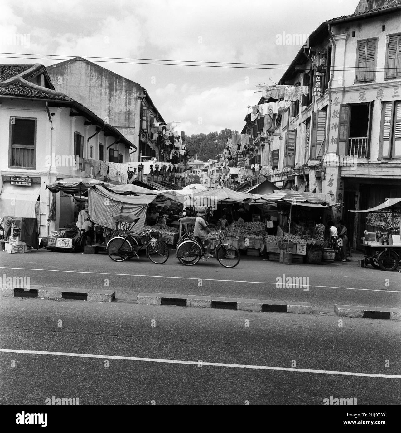 Scenes in Chinatown, Singapore, dove il vecchio incontra il nuovo. I lavaggi puliti sono spoked fuori dalle finestre da entrambi gli edifici vecchi e nuovi mentre le limousine o i trishaws eleganti fanno il loro senso durante il calore di mattina. 6th febbraio 1962. Foto Stock