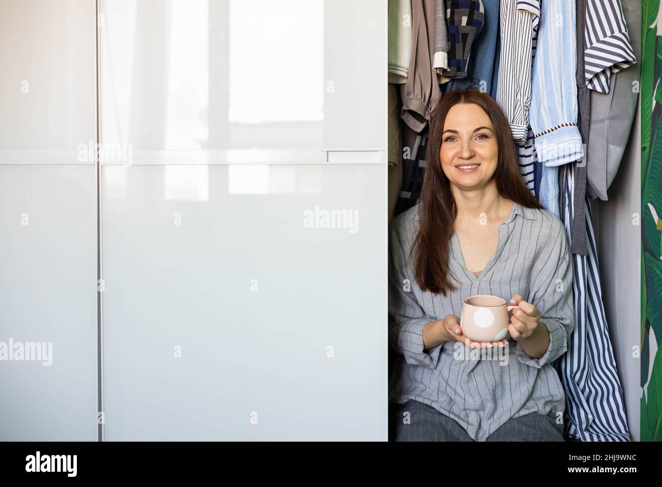 Ritratto felice donna domestica posa armadio organizzazione di stoccaggio. Design di mobili in legno Foto Stock