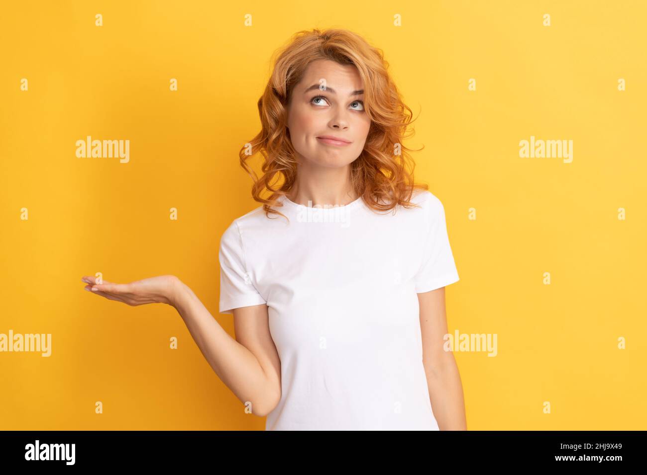 donna rossa meditante che presenta il prodotto su sfondo giallo con spazio copia Foto Stock