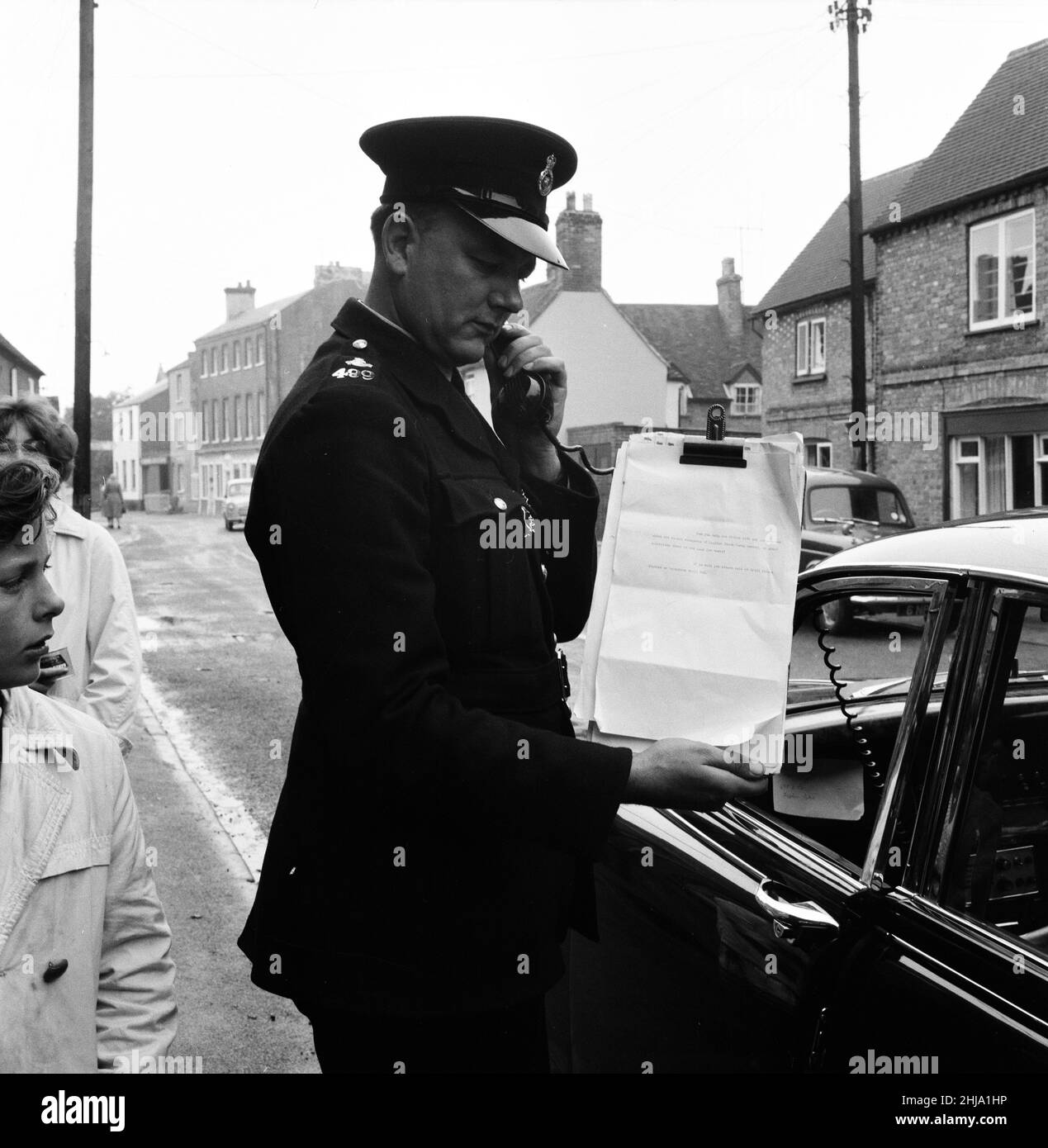 Auto di polizia dotata di un telefono altoparlante unità, appello per informazioni nel villaggio di Brill, Mercoledì 14th agosto 1963. I nostri spettacoli di foto ... Poliziotto che tiene appunti con script che sta usando per fare appello per le informazioni. Il 1963 Great Train Robbery fu la rapina di 2,6 milioni di sterline da un treno Royal Mail diretto da Glasgow a Londra sulla West Coast Main Line nelle prime ore del 8th agosto 1963, a Bridego Railway Bridge, Ledburn, vicino a Mentmore nel Buckinghamshire, Inghilterra. Foto Stock