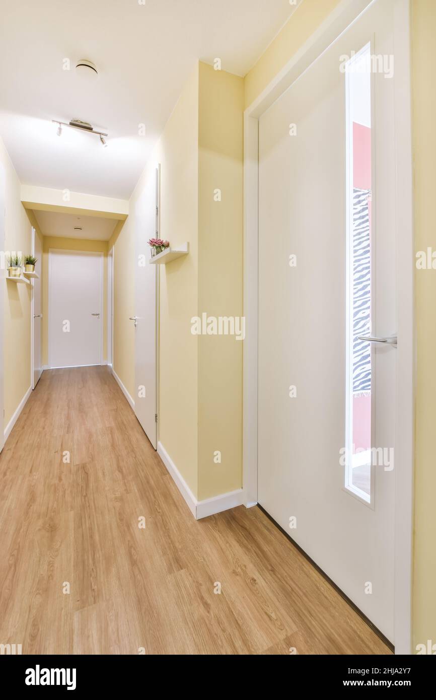 Lungo ed elegante corridoio con pareti gialle e porte bianche Foto Stock