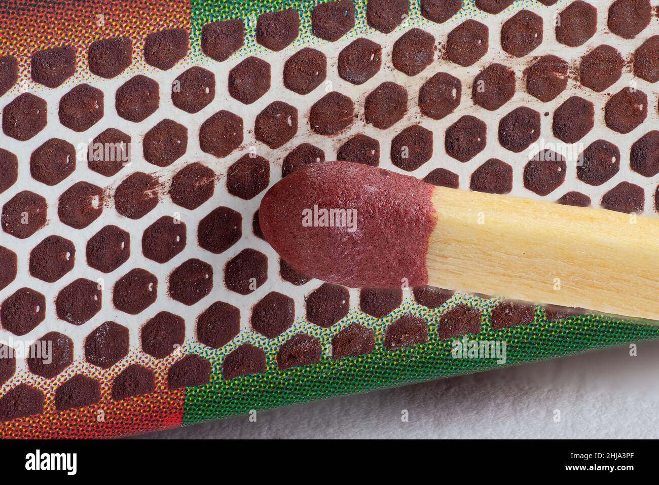 Vista ravvicinata della testa di un match stick che sta per essere illuminata contro una scatola di match Foto Stock