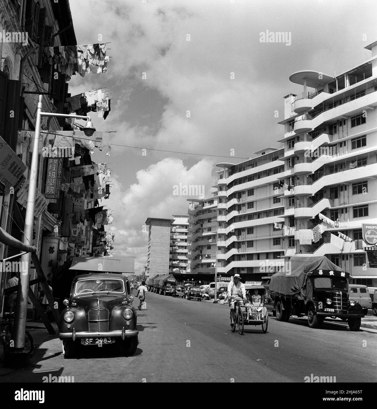 Scene a Chinatown, Singapore. Upper Hokien Street, dove il vecchio incontra il nuovo. I lavaggi puliti sono spoked fuori dalle finestre da entrambi gli edifici vecchi e nuovi mentre le limousine o i trishaws eleganti fanno il loro senso durante il calore di mattina. 6th febbraio 1962. Foto Stock