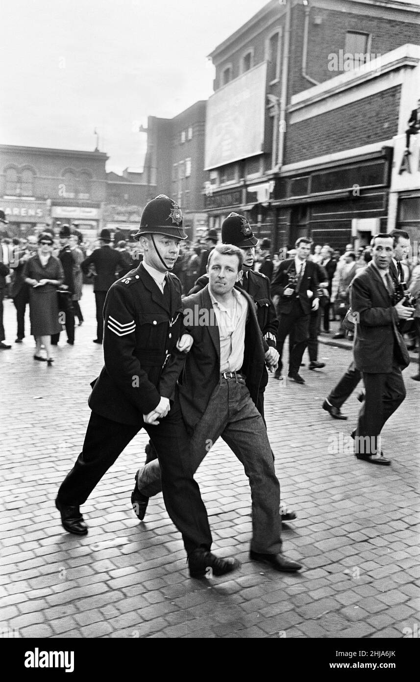 Una folla numerosa si è riunita a Ridley Road, nel E8, per dimostrare contro l'ex leader fascista Sir Oswald Mosley e i membri del suo gruppo antisemita Blackshirt che avevano pianificato un rally nell'East End di Londra. Mosley e il suo gruppo furono assaliti e punzonati a terra non appena il suo incontro si aprì a Ridley Road, Dalston. La polizia ha chiuso la riunione entro i primi tre minuti e ha fatto 54 arresti, uno dei quali era il figlio di Sir Oswald Max. La polizia arresta uno dei manifestanti arrabbiati. 31st luglio 1962. Foto Stock