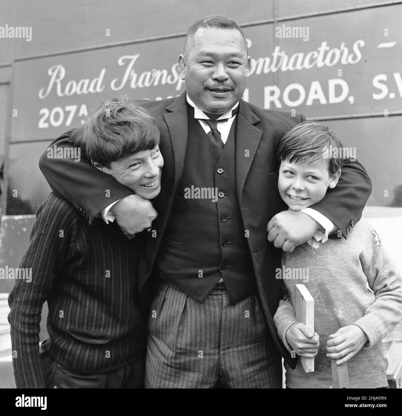 Filmare la scena del golf per 'Goldfinger' al campo da golf di Stoke Park vicino Stoke Poges, Buckinghamshire, sono stati Sean Connery ( James Bond ) Gert Frobe ( Goldfinger ) e Harold T Sakata che è meglio conosciuto come ' Tosh Togo ' nel mondo di Wrestling. Harold sta giocando la parte del caddy per questa scena. Nel film James Bond e Goldfinger giocano per un palo del £5000. Il gioco è storto dall'inizio alla fine, ma Bond vince alla fine Certo. La nostra immagine mostra, Harold T Sakata giocando a combattere con un paio di giovani cacciatori di autografi 21st maggio 1964 Foto Stock