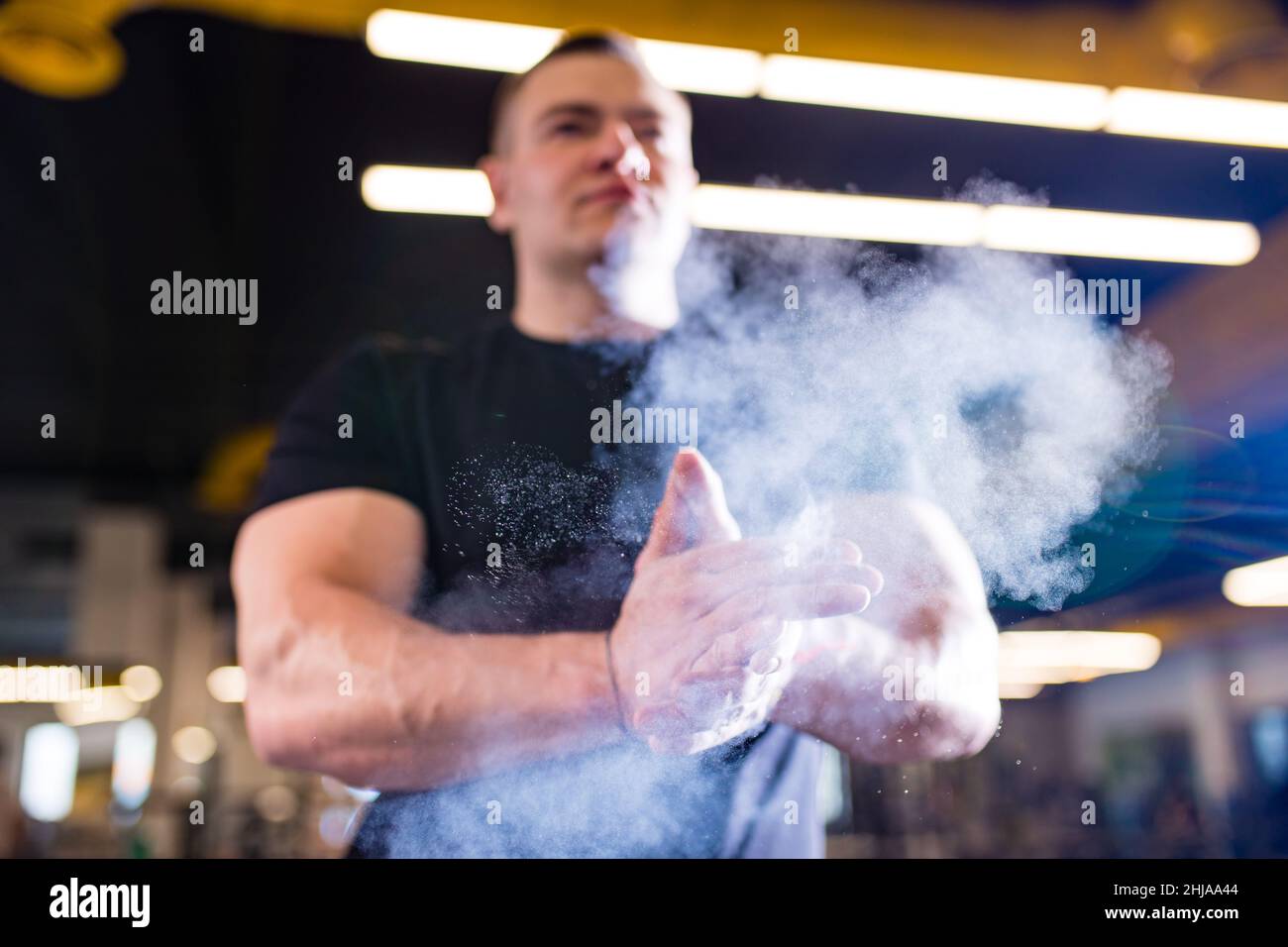 l'uomo stringe le mani con la polvere in palestra si prepara ad allenarsi Foto Stock