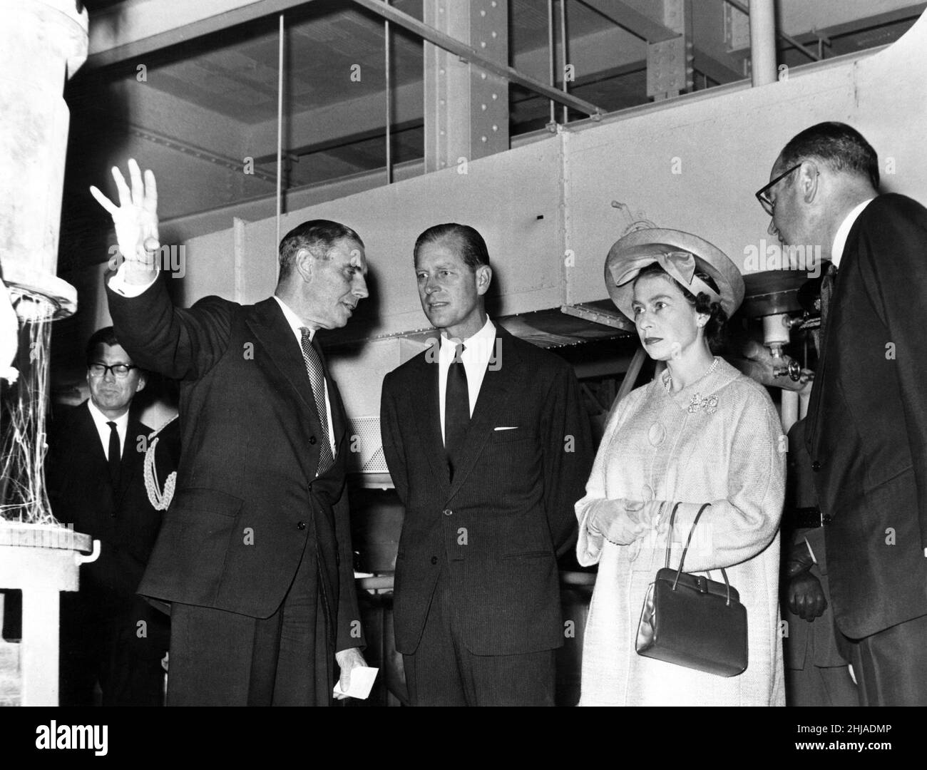 La Regina Elisabetta II e il Duca di Edimburgo visitano il Galles. Nella foto, il Sig. W Allman, Assistant Managing Director British Nylon Spinners (BNS) che spiega il processo nella Hopper Charging Room alla Regina e al Duca. A destra c'è il signor F C Bagnall, amministratore delegato della British Spinners. Pontypool, Galles. Maggio 1963. Foto Stock