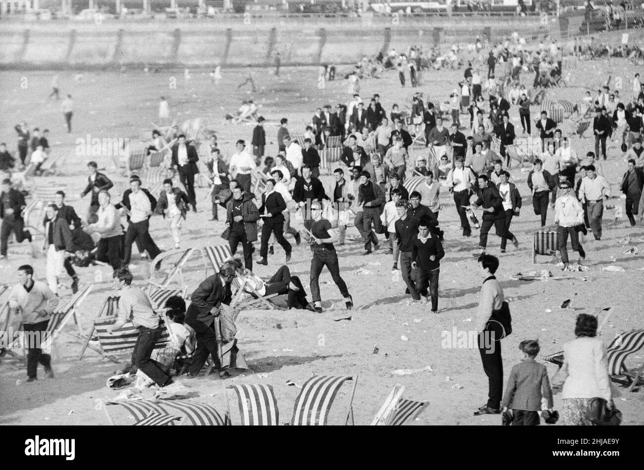 Mods / Rockers. La foto mostra la scena a Margate, nel nord-est del Kent nel maggio 1964. Mods corrono attraverso la spiaggia, disturbando i vacanzieri mentre vanno. Foto scattata il 17th maggio 1964 Foto Stock