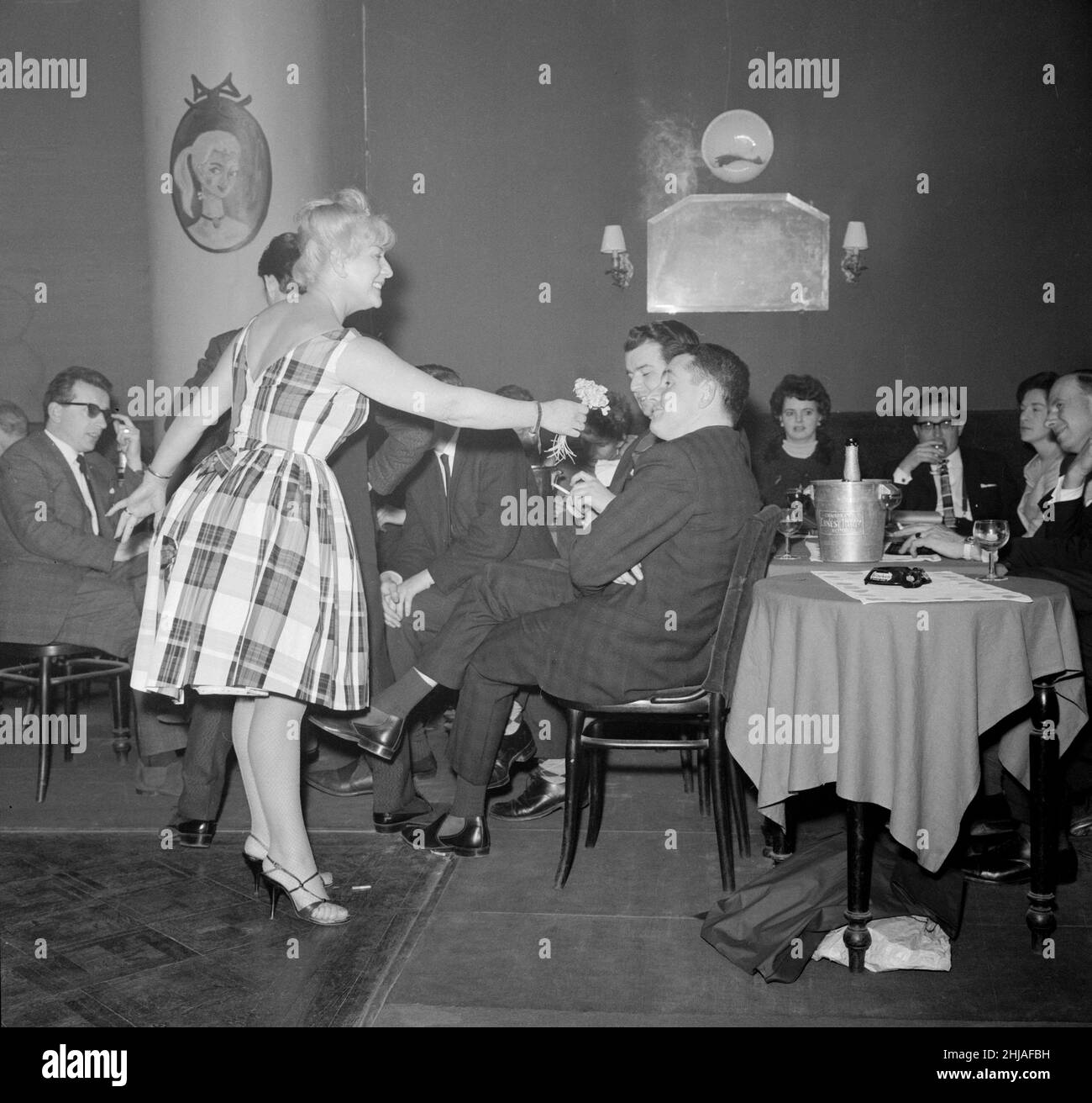 Il vincitore del Rally di Monte Carlo Paddy Hopkirk gode dell'attenzione di una hostess in un nightclub di Monte Carlo mentre celebra la sua vittoria. 25th gennaio 1964. Foto Stock