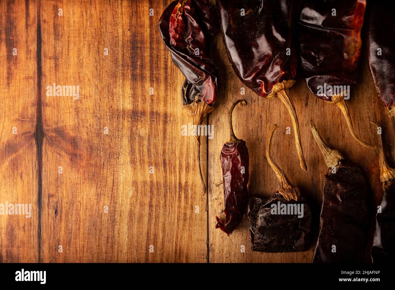 Cile Guajillo. Questo peperoncino messicano è la forma essiccata di peperoncino mirasol e viene utilizzato in una varietà di preparazioni messicane. Rustico asse di legno. Disposizione piatta Foto Stock