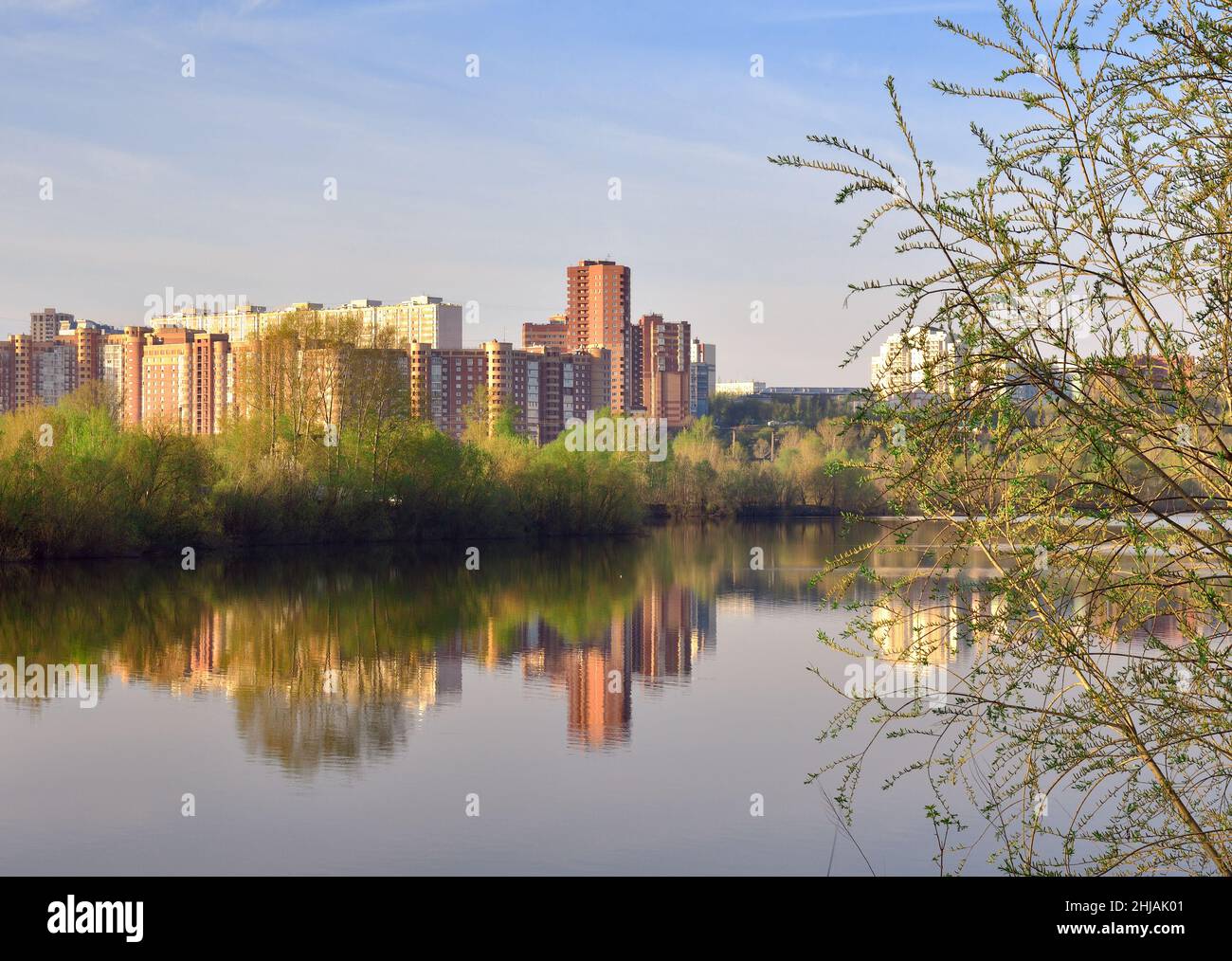 Al mattino presto, edifici a più piani sono sepolti nel verde e raggi dorati del sole, riflessi nell'acqua, cielo blu. Novosibirsk, Siberia, Rus Foto Stock