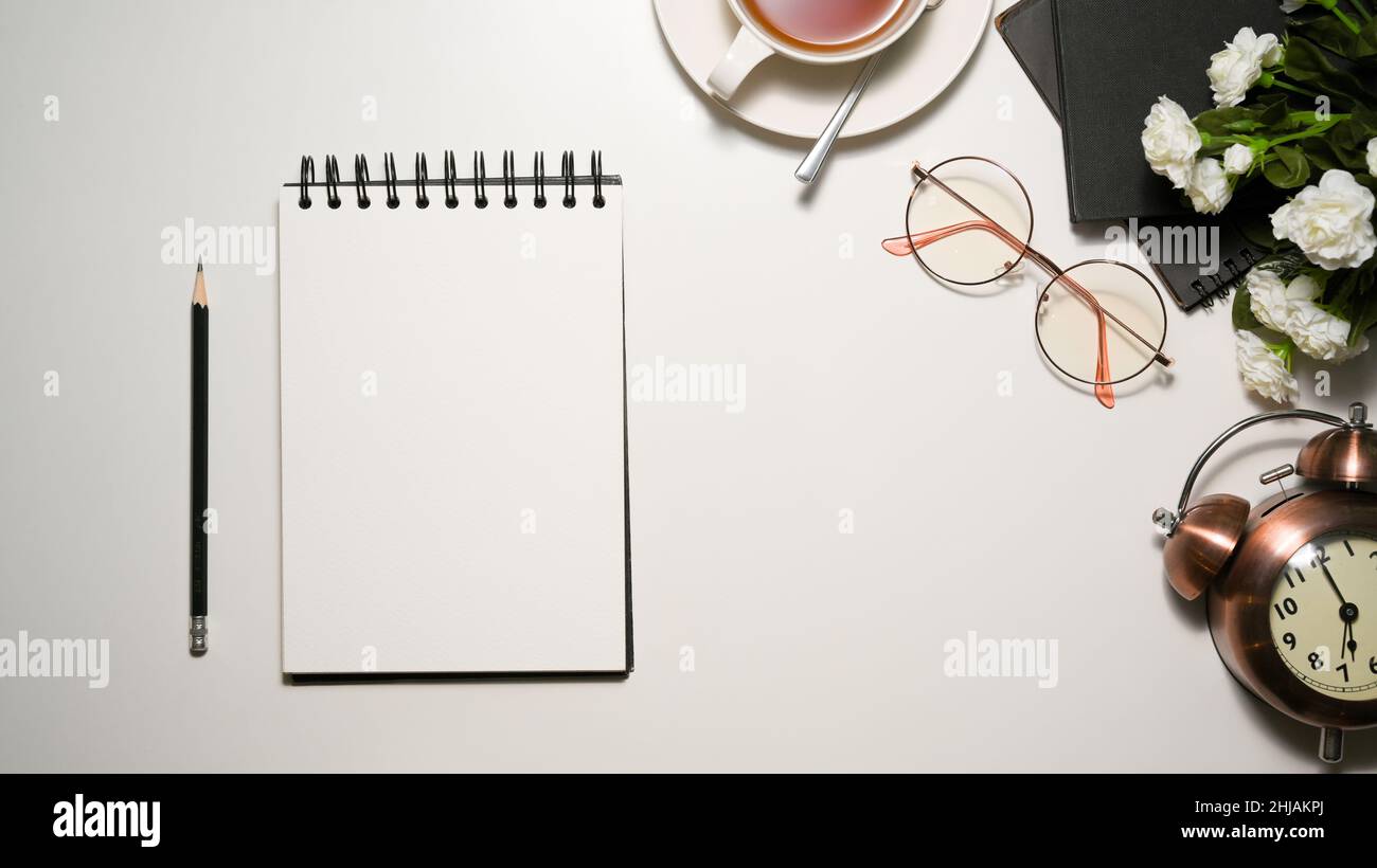 Foglio di carta con blocco note a spirale per la visualizzazione del testo nella scrivania da ufficio bianca. Vista dall'alto Foto Stock