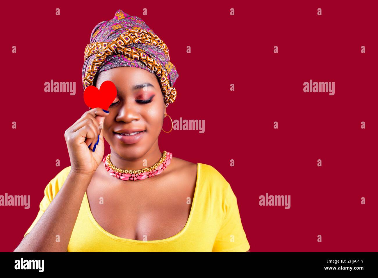 attraente bella donna sud con turbante tenuta in mani cuore isolato su sfondo rosso san valentino giorno 14 febbraio Foto Stock