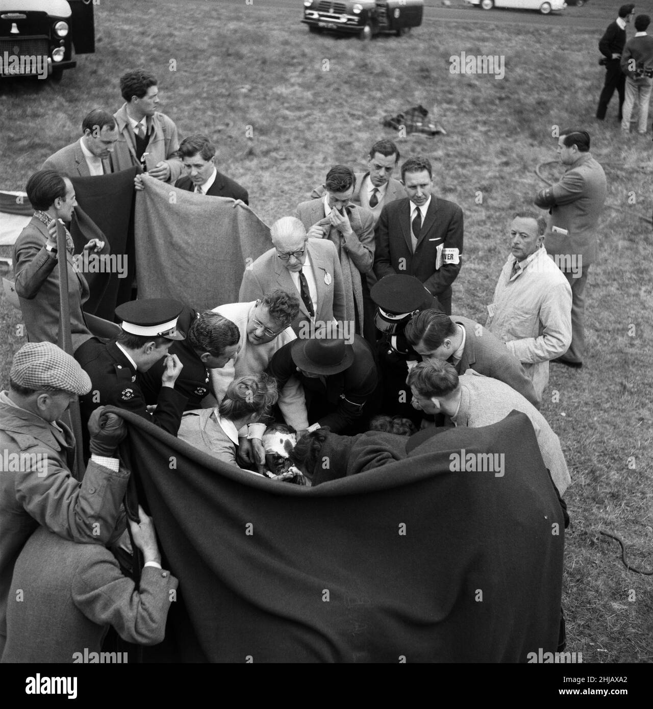 Gare automobilistiche a Goodwood. Il pilota di corse ACE Stirling Moss ha avuto una fuga miracolosa dalla morte quando si è schiantato a 120 miglia all'ora. Nella foto, Moss è seguito da un infermiere e da un medico. 23rd aprile 1962. Foto Stock