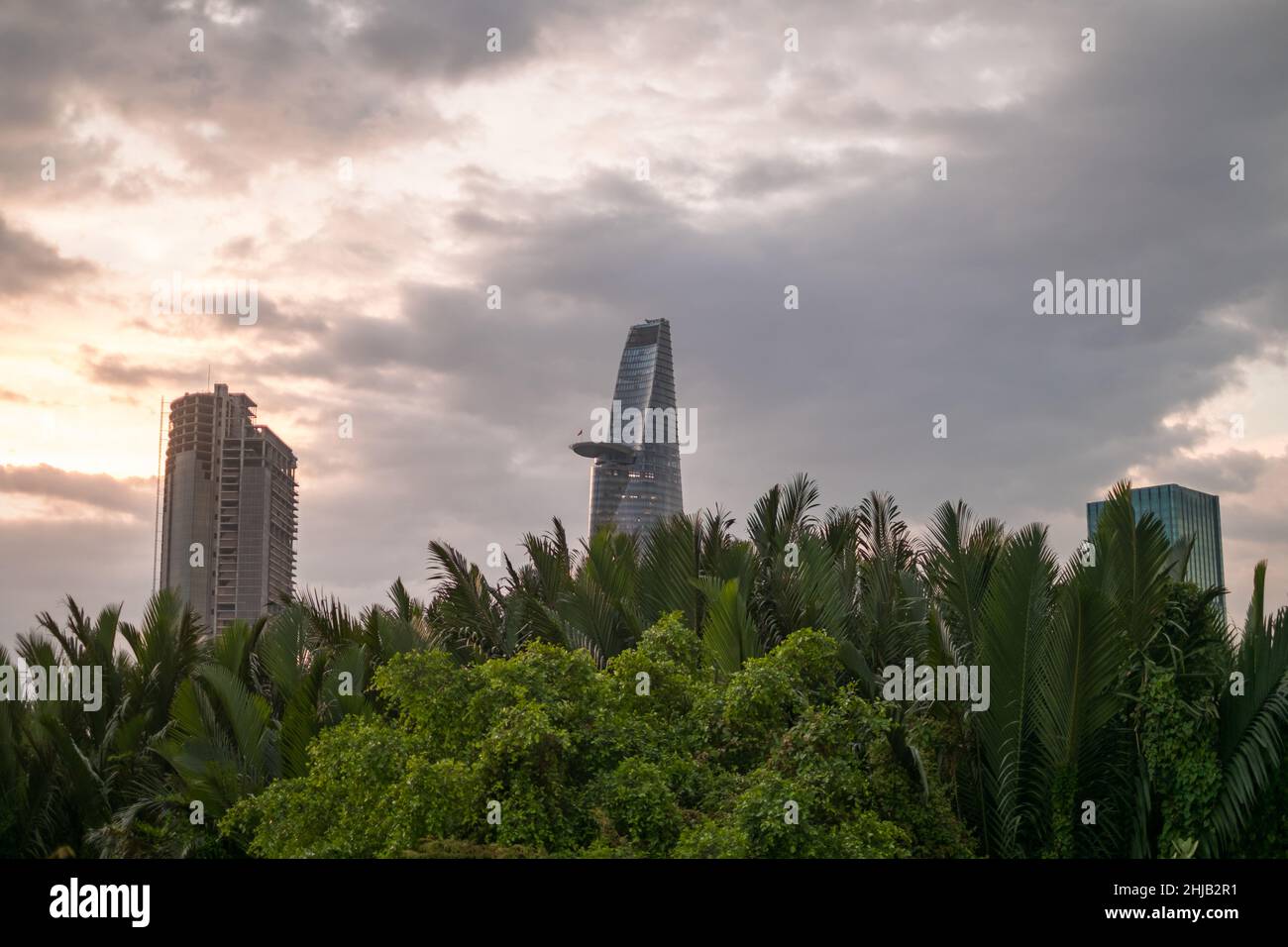Foto di grattacieli al tramonto nel parco con erba verde e alberi. Vista sulla metropoli con edifici moderni. Foto di alta qualità Foto Stock