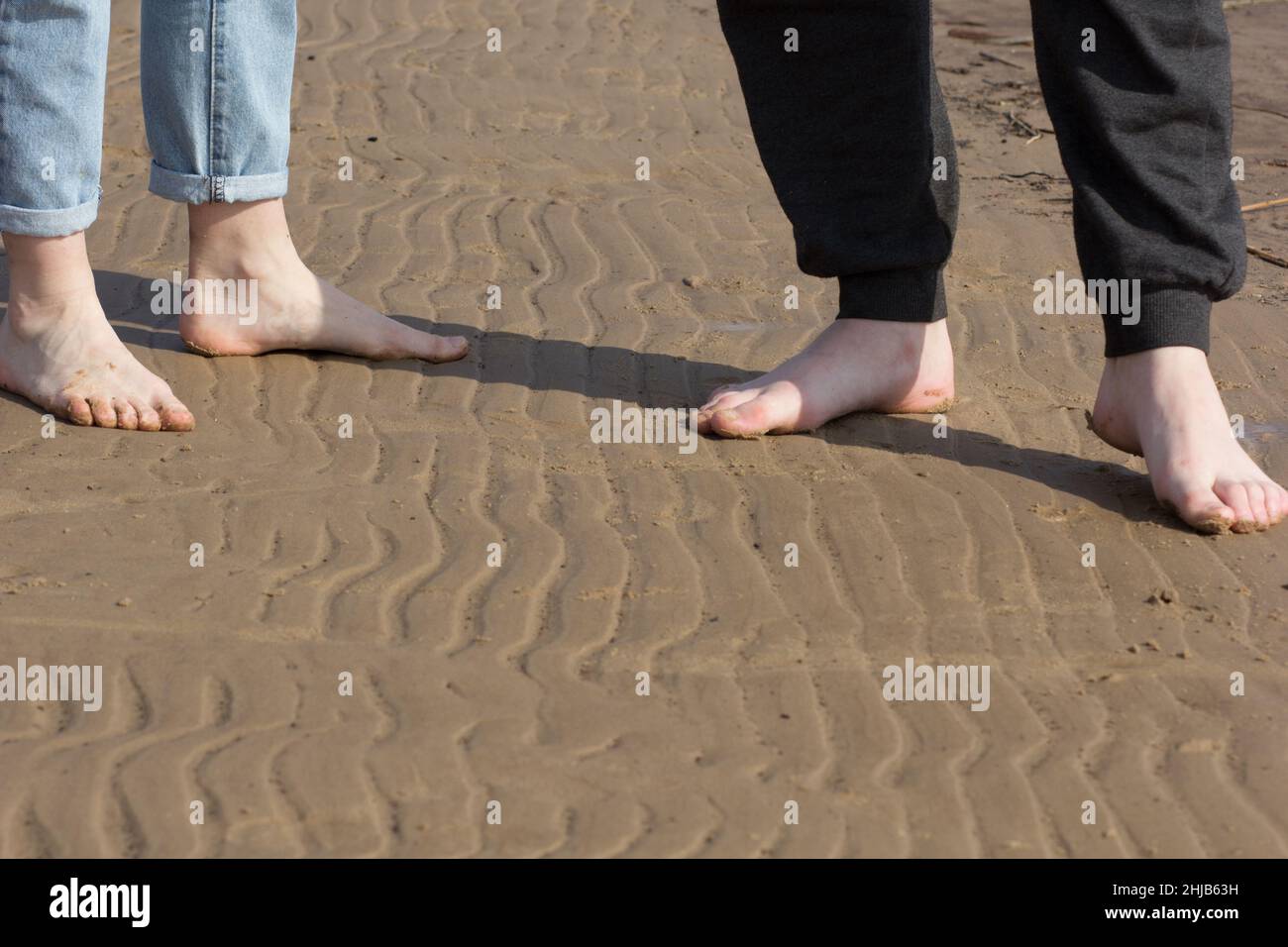 Piedi donna e piedi uomo a piedi nudi in piedi in piedi l'uno di fronte all'altro sulla spiaggia di sabbia Foto Stock