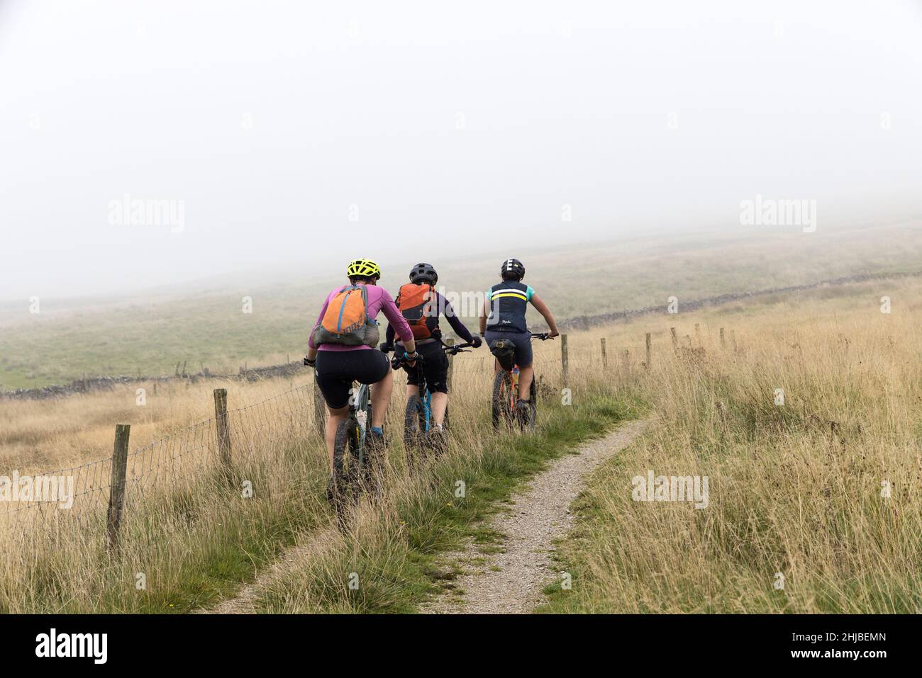 Tre ciclisti in mountain bike in pista, Langcliff, Yorkshire Dales, Inghilterra, Regno Unito Foto Stock