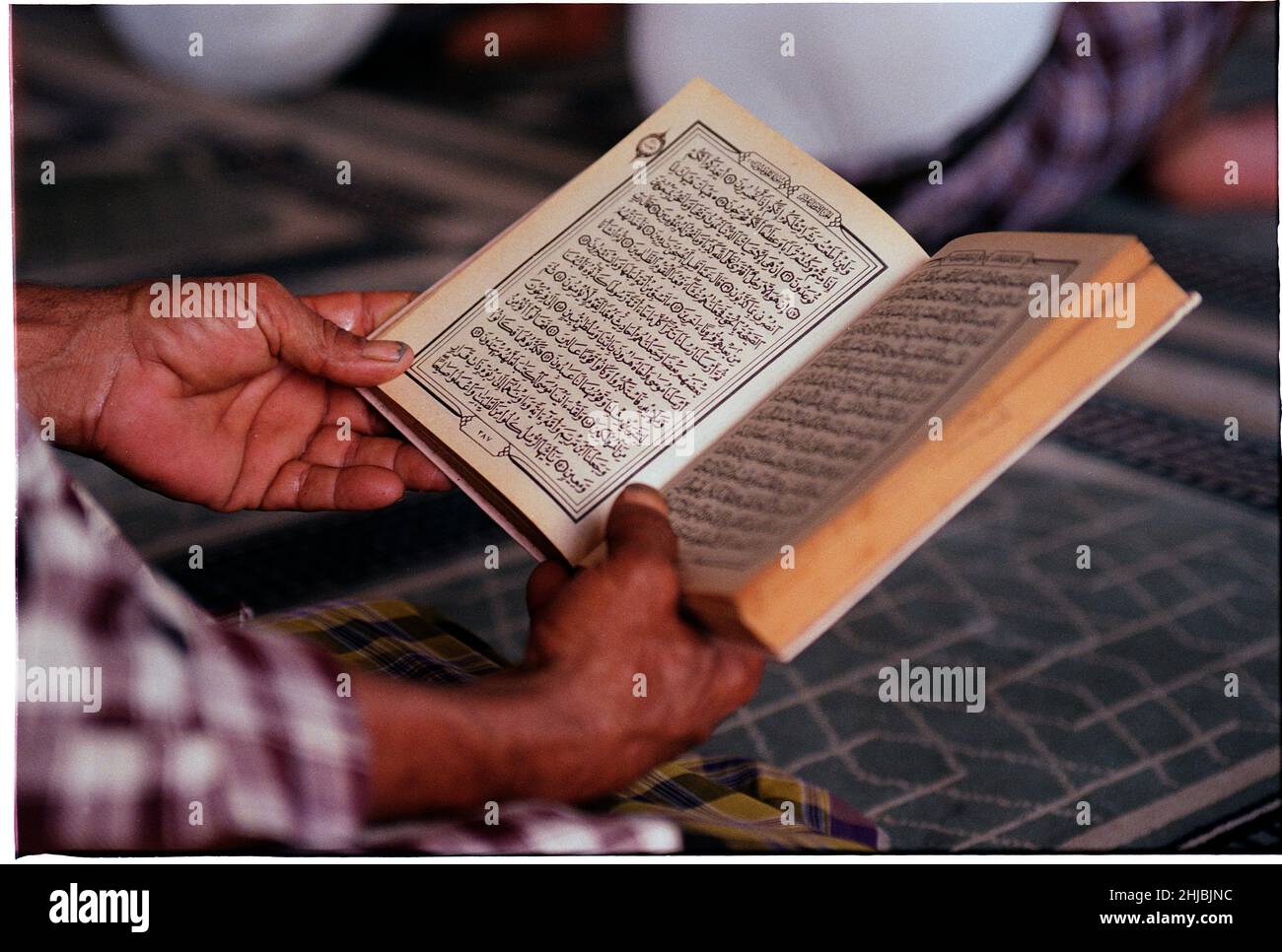Uomo che detiene una copia dell'antico Corano, in una moschea di Sana'a, la più grande città e capitale dello Yemen, paese in Medio Oriente Foto Stock