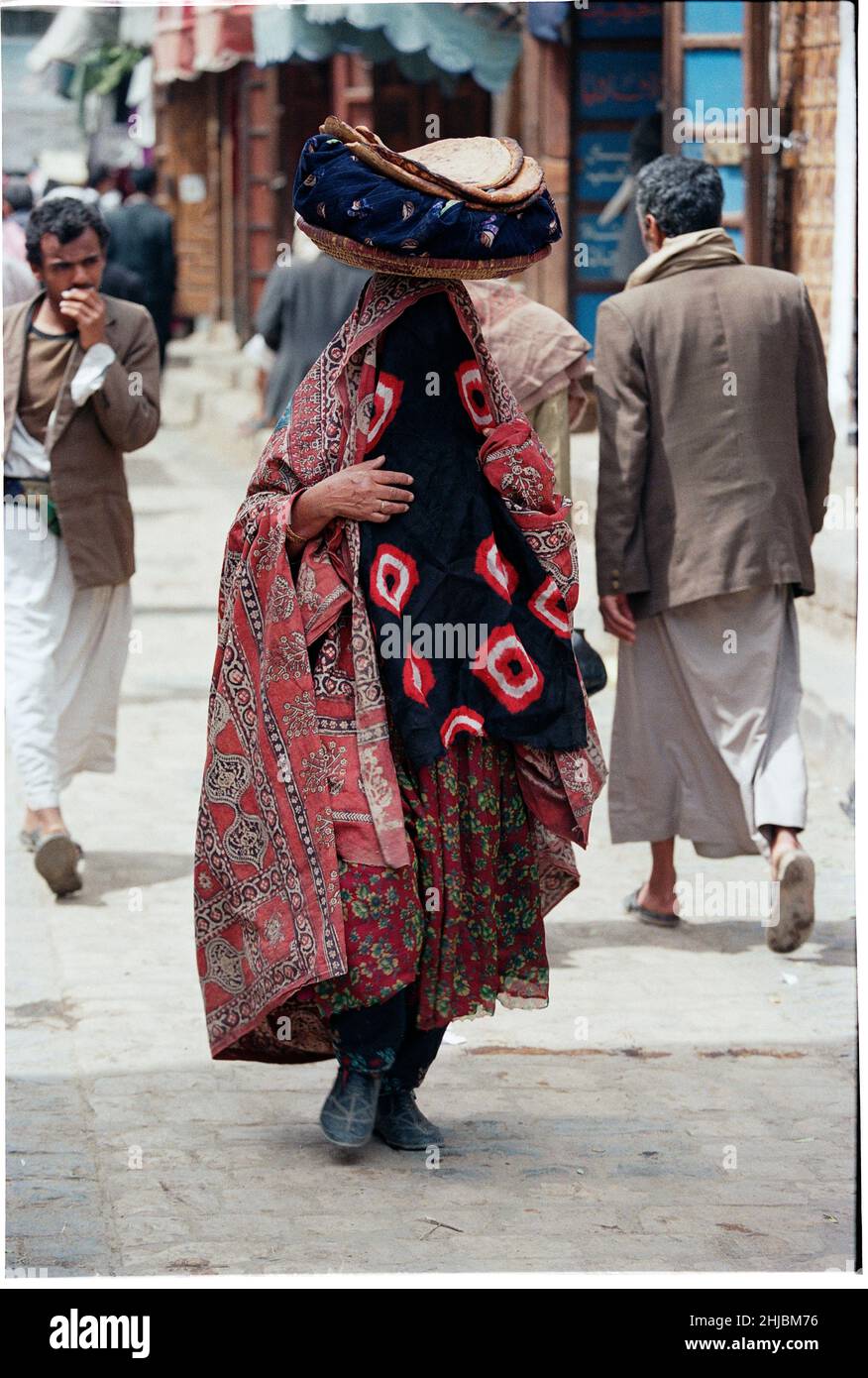 Una donna che porta pane piatto malooga, attraverso i mercati di Sana'a, la più grande città e capitale dello Yemen, paese in Medio Oriente Foto Stock