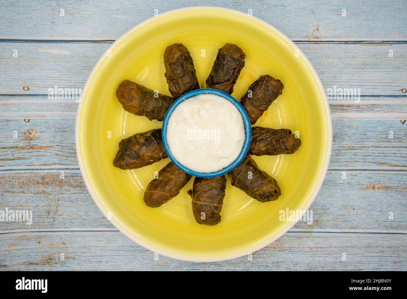 Confezionamento di foglie di carne. Sapore mediterraneo tradizionale. Foglie avvolte con yogurt su sfondo di legno blu. Nome locale etli yaprak sarma Foto Stock