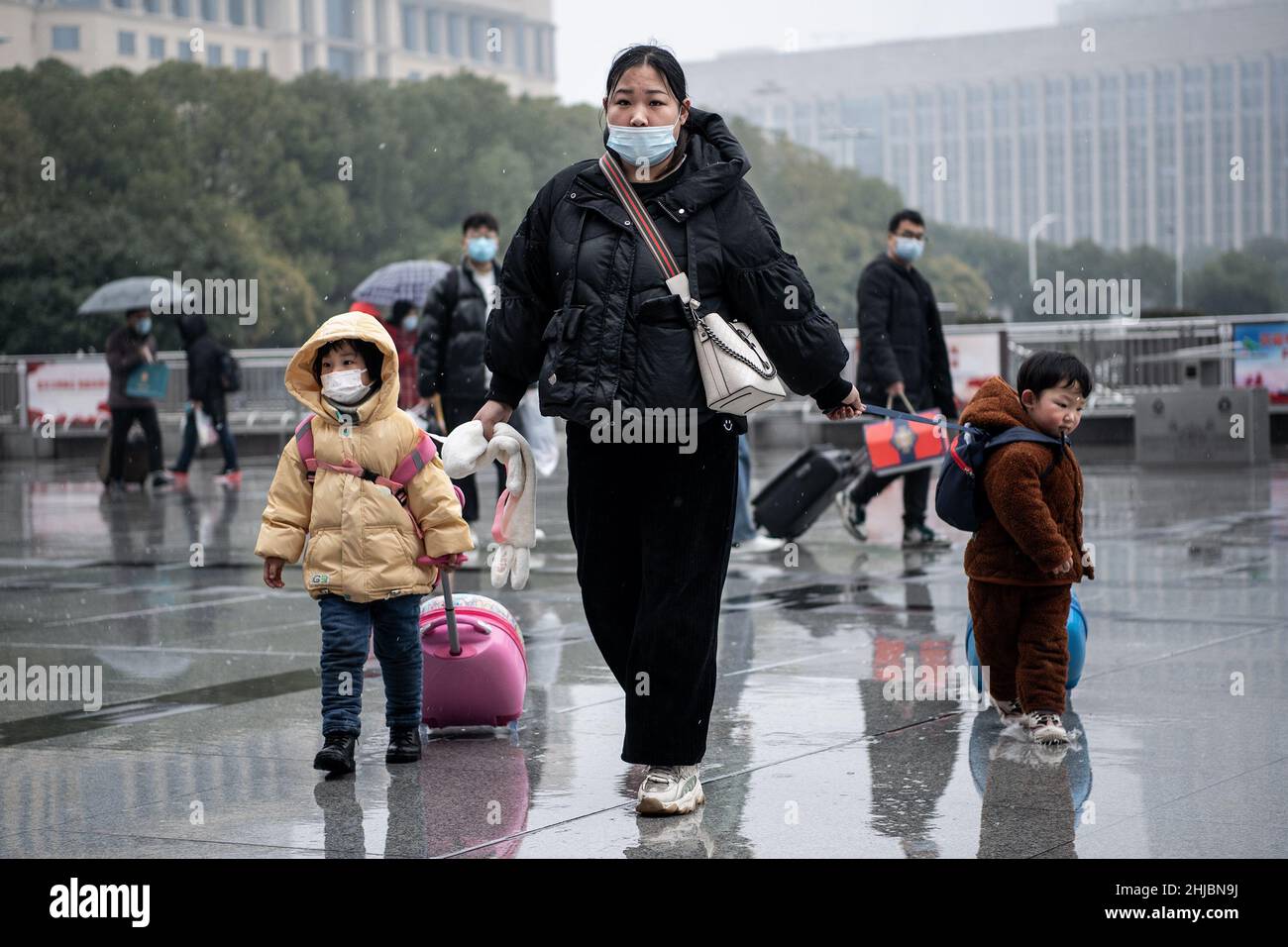 Wuhan, Cina. 28th Jan 2022. Una donna con i suoi figli cammina nella nevicata alla stazione ferroviaria di Hankou a Wuhan.Un totale di 2,8 miliardi di viaggi passeggeri sono attesi durante i 40 giorni 'Chunyun, ' o Spring Festival corsa, che ha iniziato dal 17 gennaio di quest'anno. Milioni di cinesi si recheranno a casa per visitare le famiglie in massa durante il periodo di festa di Primavera che inizia con il Capodanno lunare il 1 febbraio. (Foto di Ren Yong/SOPA Images/Sipa USA) Credit: Sipa USA/Alamy Live News Foto Stock